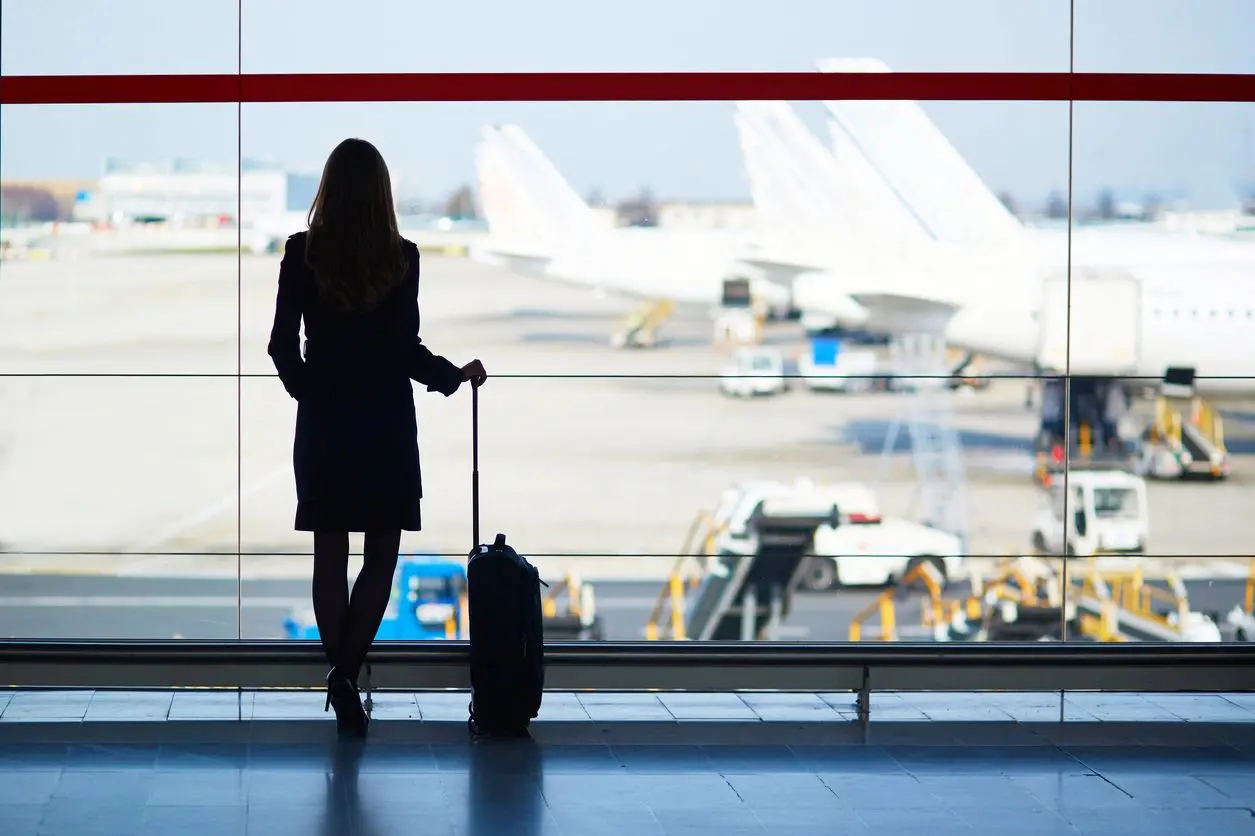 A woman standing in front of an airport window.